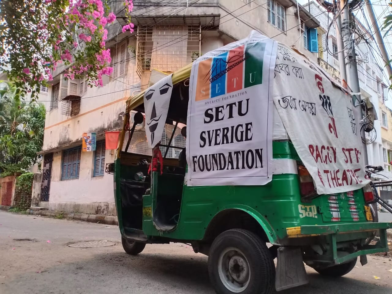An auto-rickshaw carrying a Setu Sverige Foundation banner through a neighbourhood street during a community awareness drive